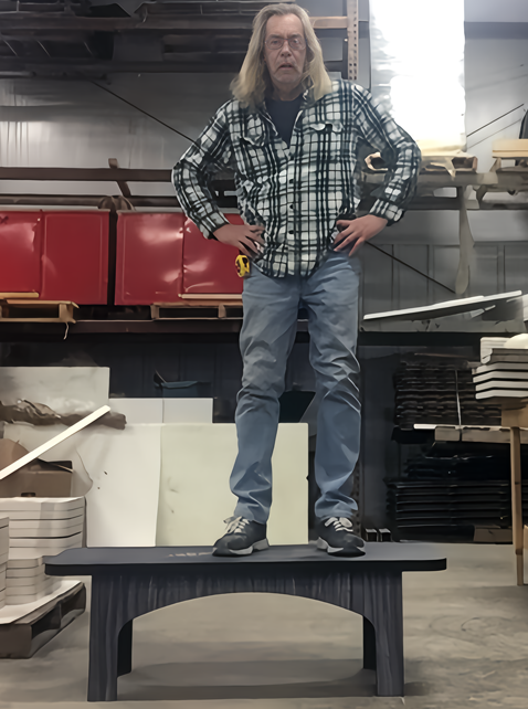 Man standing on a laminate table to demonstrate strength and durability in a workshop